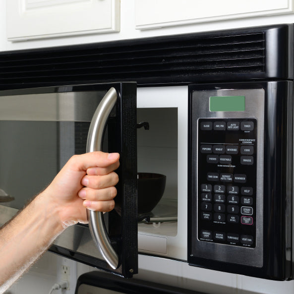 What is the principle of a microwave oven and how does it work?